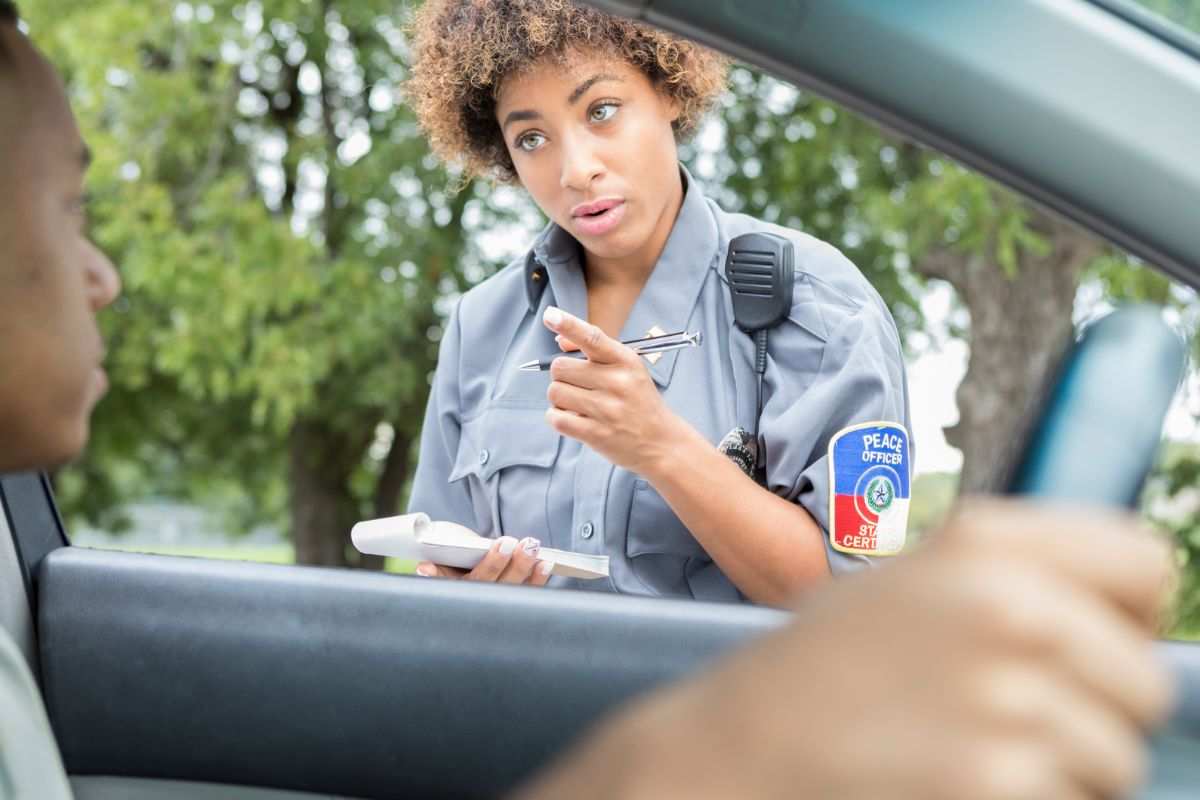 poliziotta che ferma auto e parla con conducente